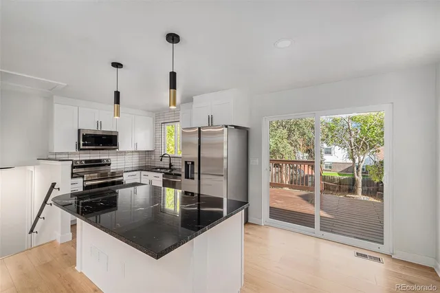 a kitchen with stainless steel appliances granite countertop a sink a stove and a refrigerator