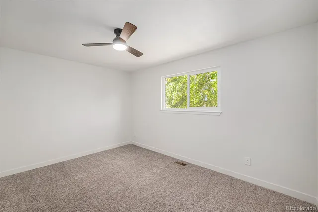 an empty room with windows and fan