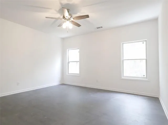 an empty room with a ceiling fan and a window