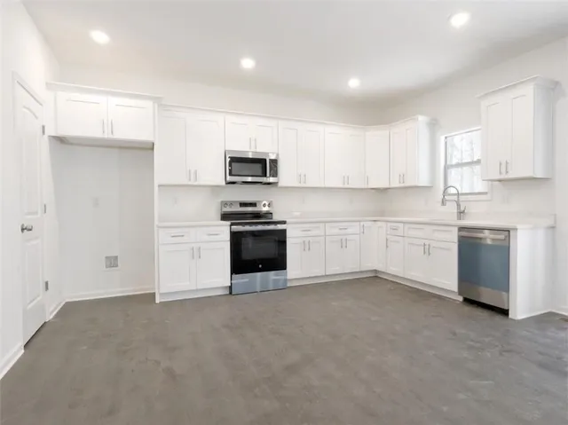 a kitchen with white cabinets stainless steel appliances and a window