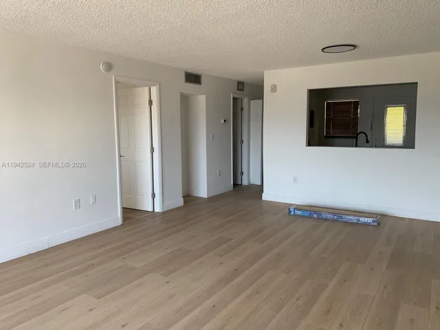 a view of an empty room with wooden floor and window