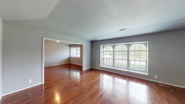 an empty room with wooden floor and windows