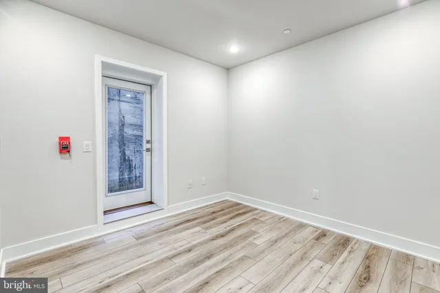 an empty room with wooden floor and fan