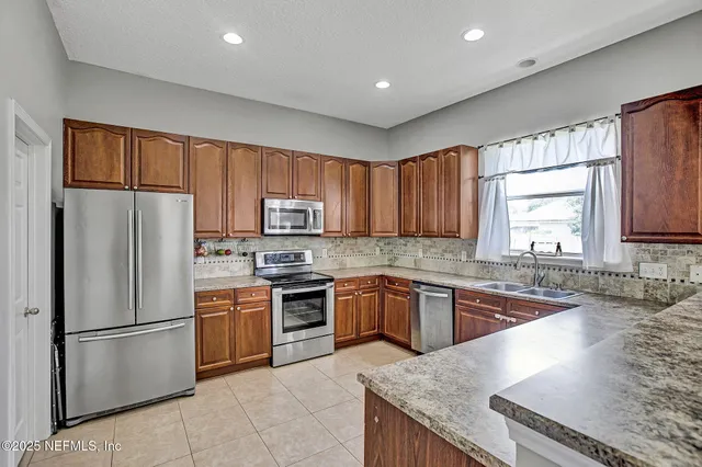 a kitchen with granite countertop stainless steel appliances a refrigerator sink stove microwave and cabinets