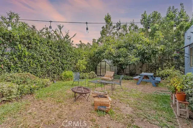 a view of a backyard with table and chairs potted plants and large tree