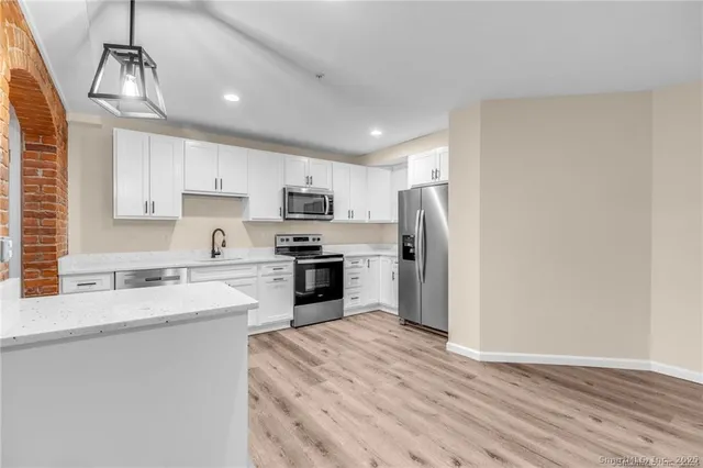 a kitchen with granite countertop a refrigerator stove top oven and sink