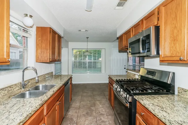 a kitchen with granite countertop a sink stove and cabinets