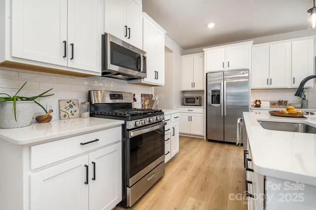 a kitchen with stainless steel appliances kitchen island granite countertop a sink stove and refrigerator