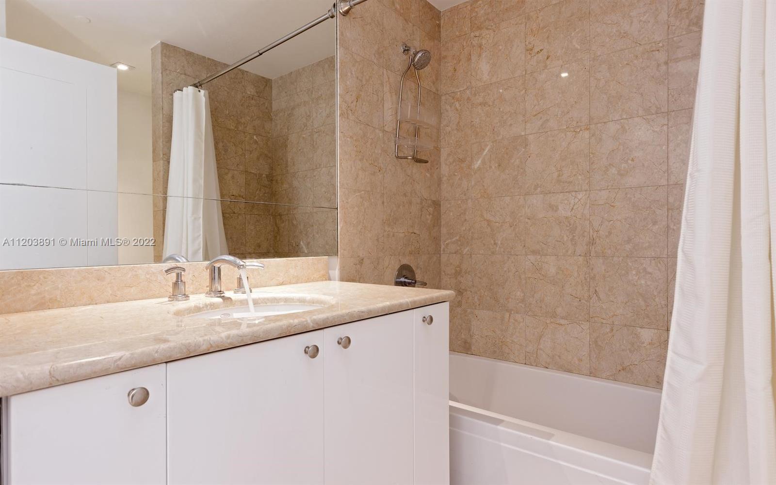 901 Brickell Key Boulevard, Unit 2503 Miami, FL 33131 - Photo 17 of 19 a bathroom with a granite countertop sink a mirror and a bathtub