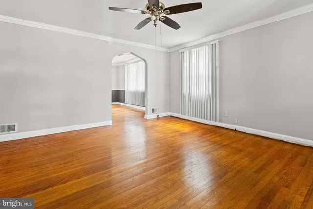 an empty room with wooden floor fan and windows