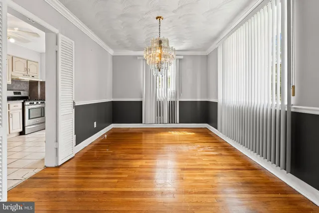a view of a room with wooden floor chandeliers and kitchen view