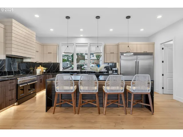 a kitchen with stainless steel appliances kitchen island granite countertop a dining table chairs sink and cabinets