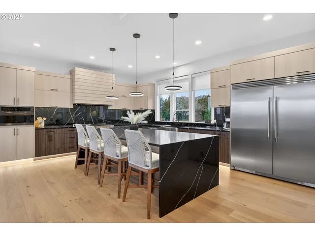 a kitchen with stainless steel appliances kitchen island granite countertop a table chairs and a refrigerator