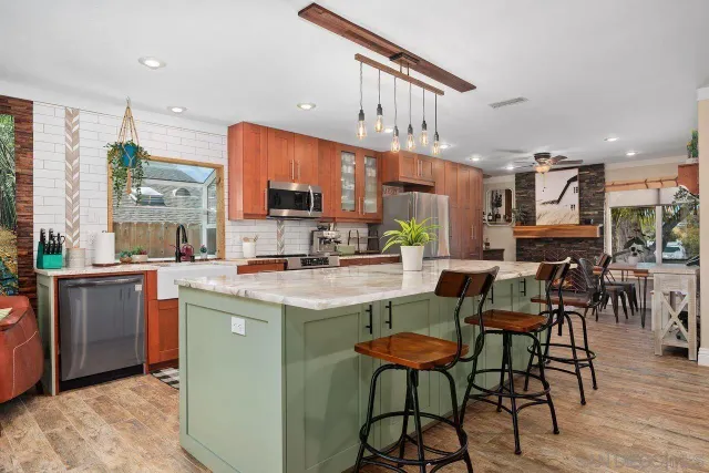 a kitchen with stainless steel appliances kitchen island granite countertop a table chairs and a refrigerator