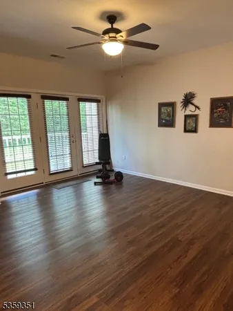 a view of empty room with wooden floor and fan