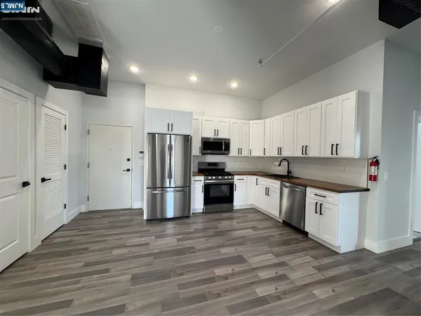 a large kitchen with stainless steel appliances and white cabinets