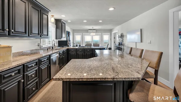 a kitchen with stainless steel appliances kitchen island granite countertop a sink stove and refrigerator