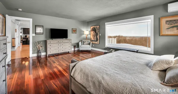 a bedroom with wooden floor and large window
