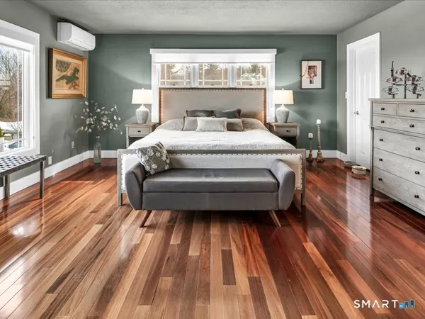 a spacious bedroom with a bed and wooden floor