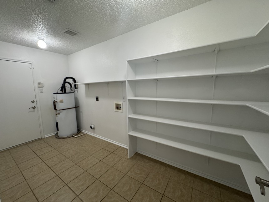 2009 Marysol Trail Cedar Park, TX 78613 - Photo 5 of 15 Laundry room featuring a textured ceiling, water heater, light tile patterned floors, washer hookup, and hookup for an electric dryer