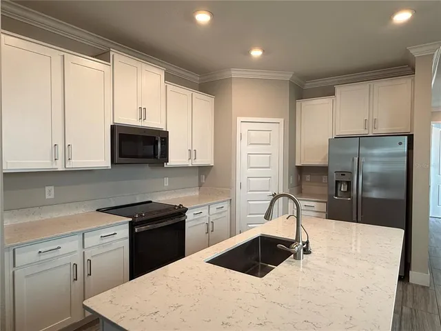 a kitchen with a refrigerator sink and cabinets