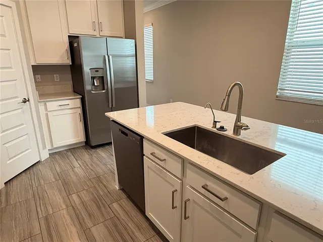 a kitchen with stainless steel appliances kitchen island a refrigerator sink and cabinets
