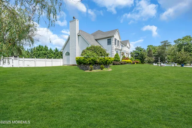 a view of a house with a big yard potted plants and large tree