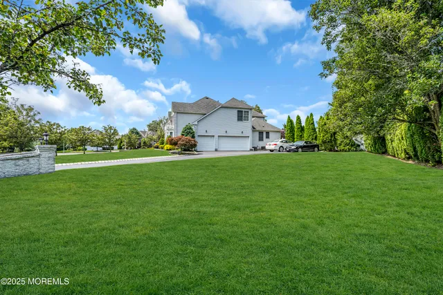 a view of a big house with a big yard and large trees