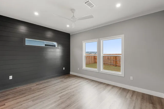 an empty room with wooden floor and windows