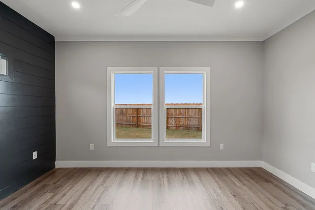 an empty room with wooden floor and windows