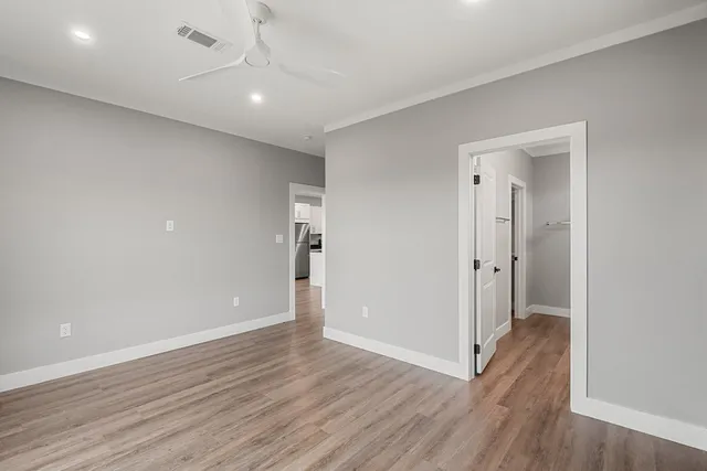 an empty room with wooden floor and windows