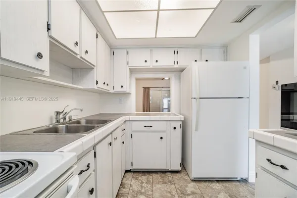 a kitchen with a sink a refrigerator and cabinets