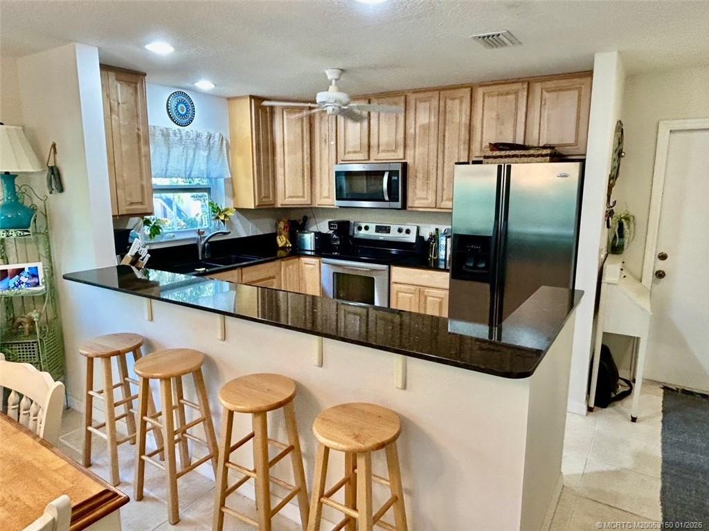 2950 Southeast Ocean Boulevard, Unit 546 Stuart, FL 34996 - Photo 12 of 33 a kitchen with stainless steel appliances granite countertop a refrigerator a stove a sink dishwasher and white cabinets with wooden floor