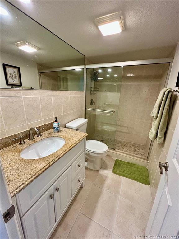 2950 Southeast Ocean Boulevard, Unit 546 Stuart, FL 34996 - Photo 17 of 33 a bathroom with a granite countertop sink a toilet a mirror and shower