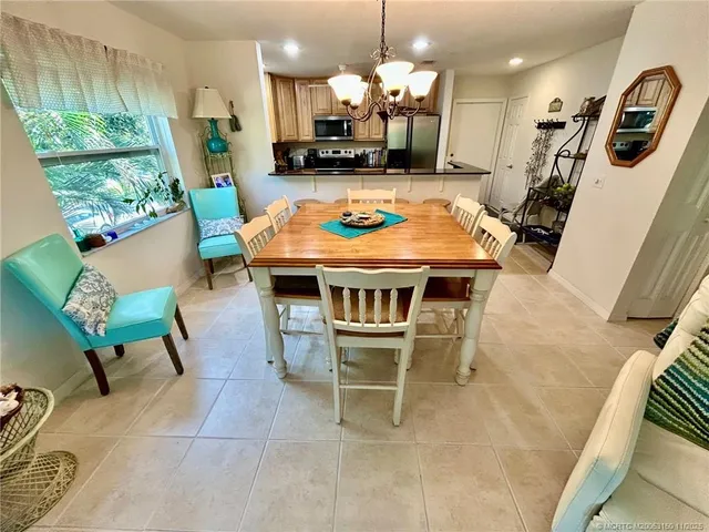a living room with couches a chandelier and a dining table with wooden floor