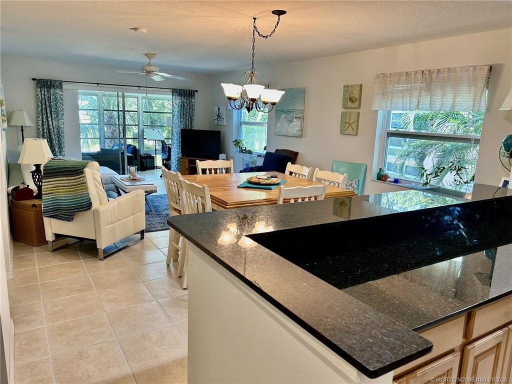 2950 Southeast Ocean Boulevard, Unit 546 Stuart, FL 34996 - Photo 10 of 33 a living room with couches a chandelier and a dining table with wooden floor