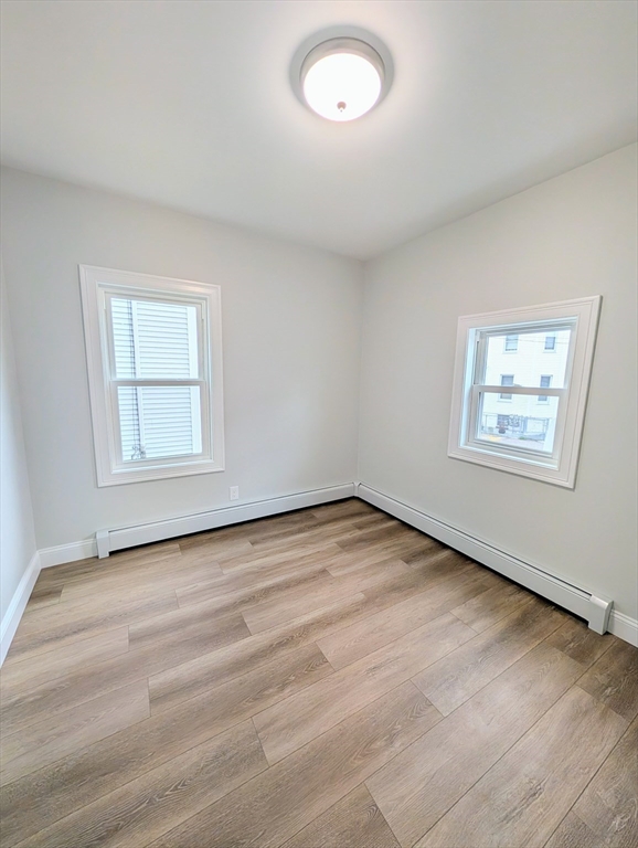 121 Whitman Street, Unit 2 New Bedford, MA 02745 - Photo 5 of 11 an empty room with wooden floor and windows