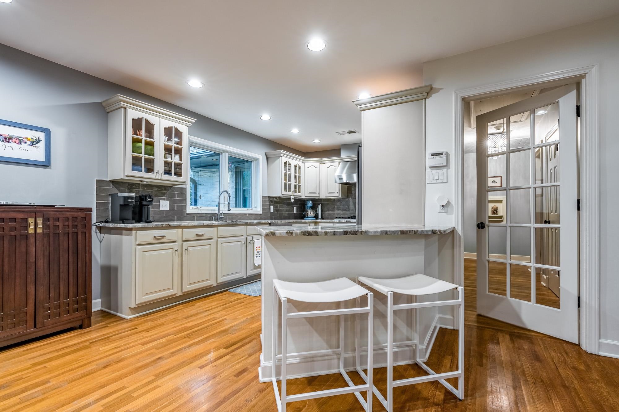 5179 Shady Grove Road Memphis, TN 38117 - Photo 13 of 25 a kitchen with kitchen island granite countertop wooden floors and white cabinets