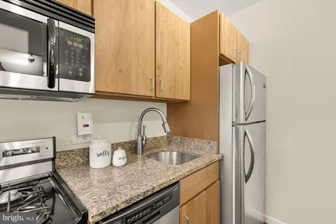 a kitchen with stainless steel appliances granite countertop a sink and a refrigerator