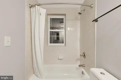 a bathroom with a bathtub shower and toilet