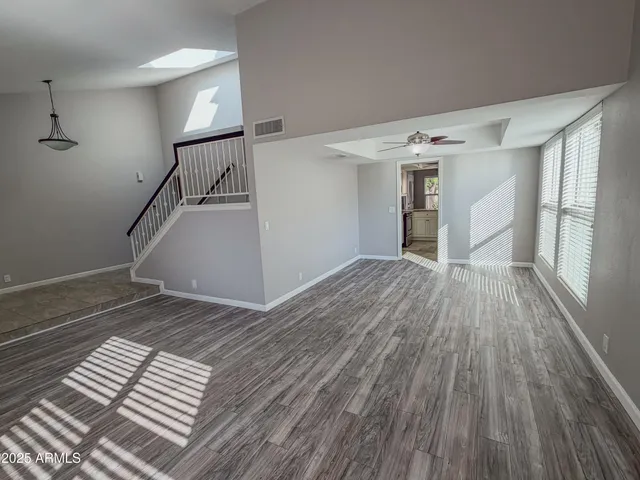 a view of empty room with wooden floor and fan