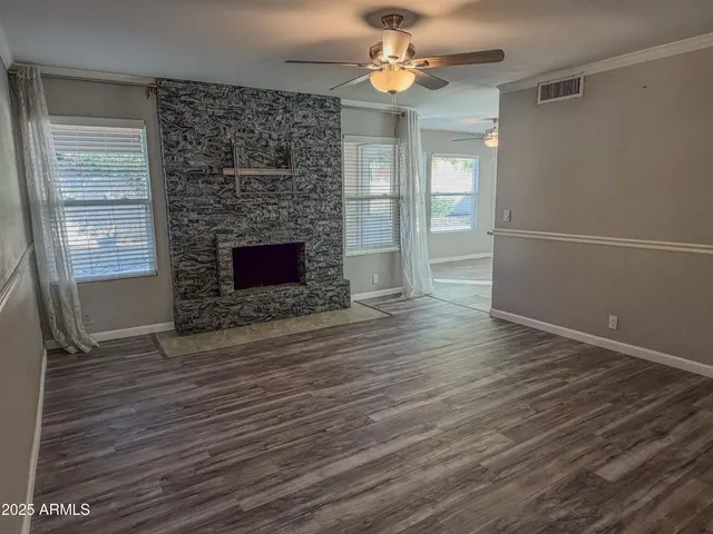 an empty room with wooden floor fireplace and windows