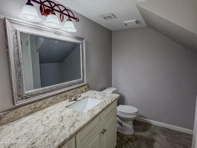 a bathroom with a granite countertop toilet a sink and mirror