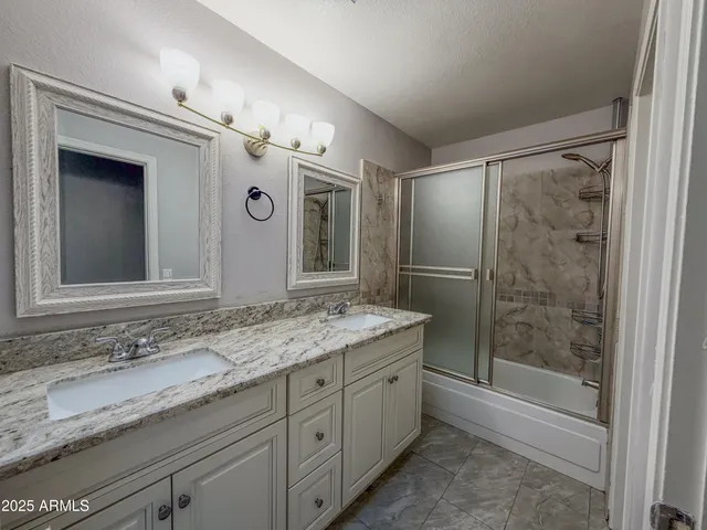 a bathroom with a granite countertop sink mirror and a shower