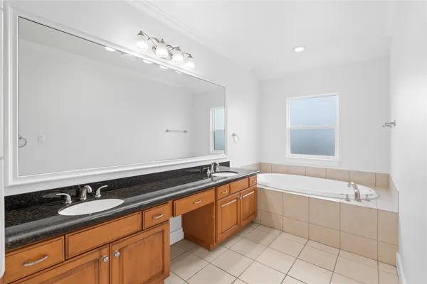 a spacious bathroom with a granite countertop sink a mirror and a bathtub