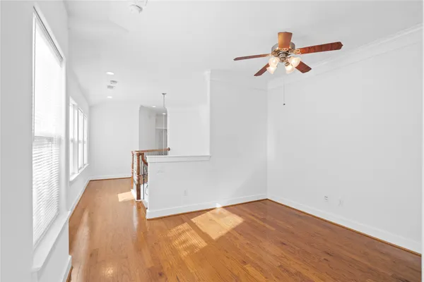 a view of empty room with wooden floor and fan