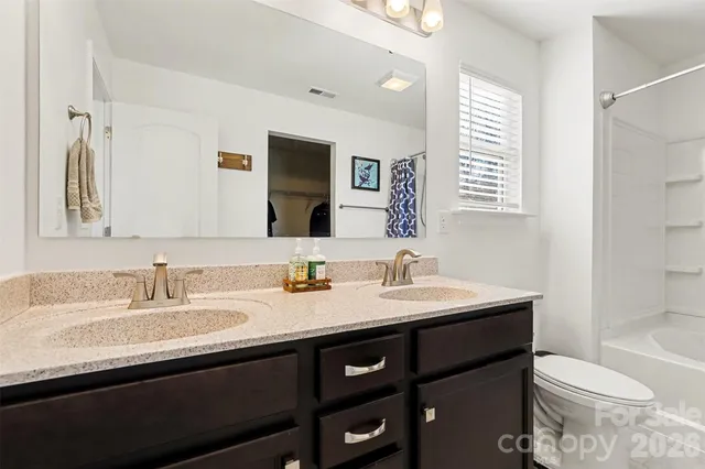a bathroom with a double vanity sink toilet and mirror