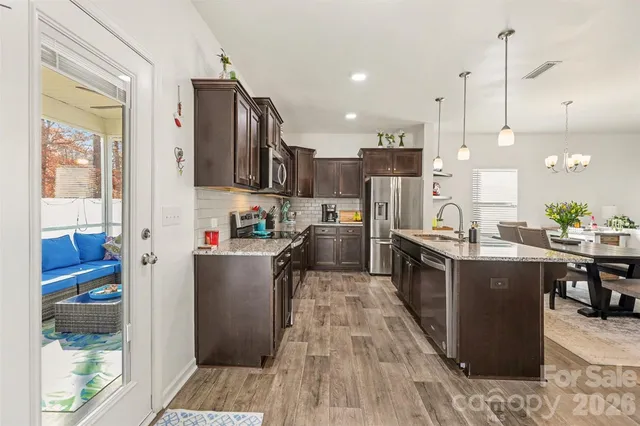 a kitchen with stainless steel appliances granite countertop a refrigerator a stove top oven a sink dishwasher and wooden cabinets