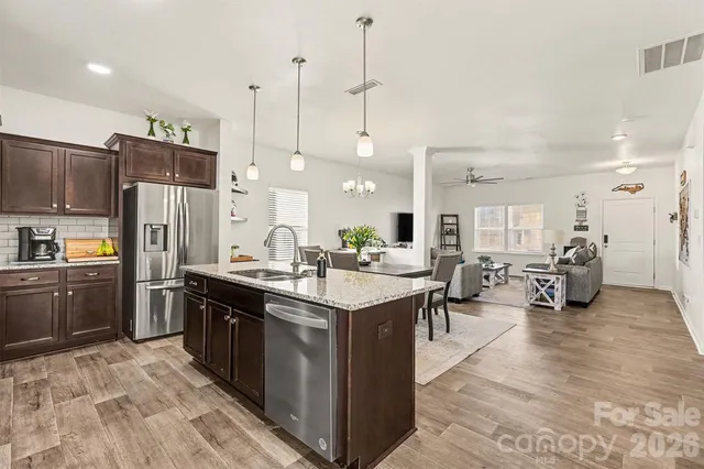 a kitchen with stainless steel appliances kitchen island granite countertop a sink a stove and a refrigerator