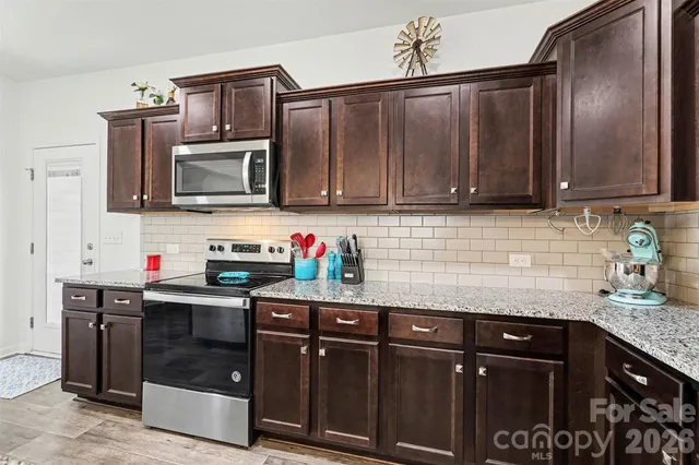 a kitchen with granite countertop a sink dishwasher stove and cabinets with wooden floor
